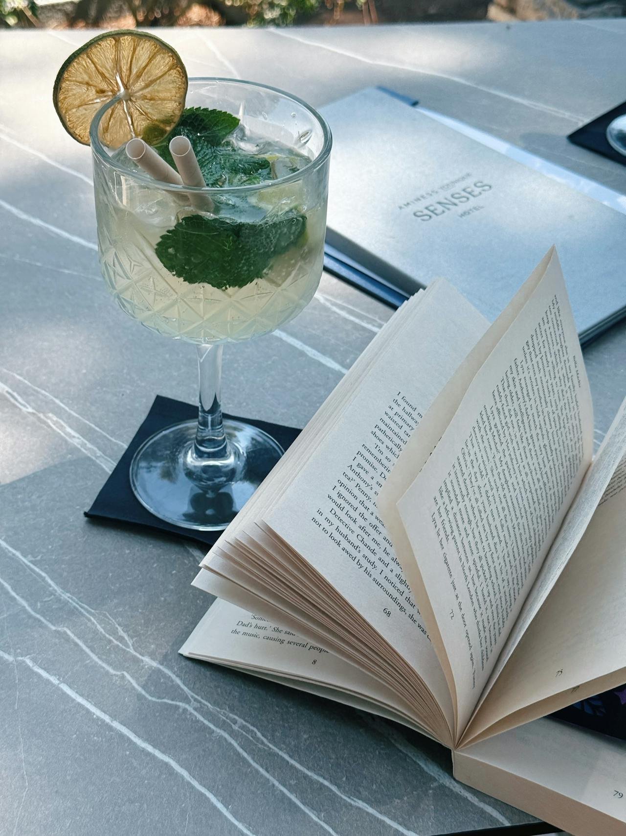 a mocktail with a dried fruit garnish and fresh mint next to books