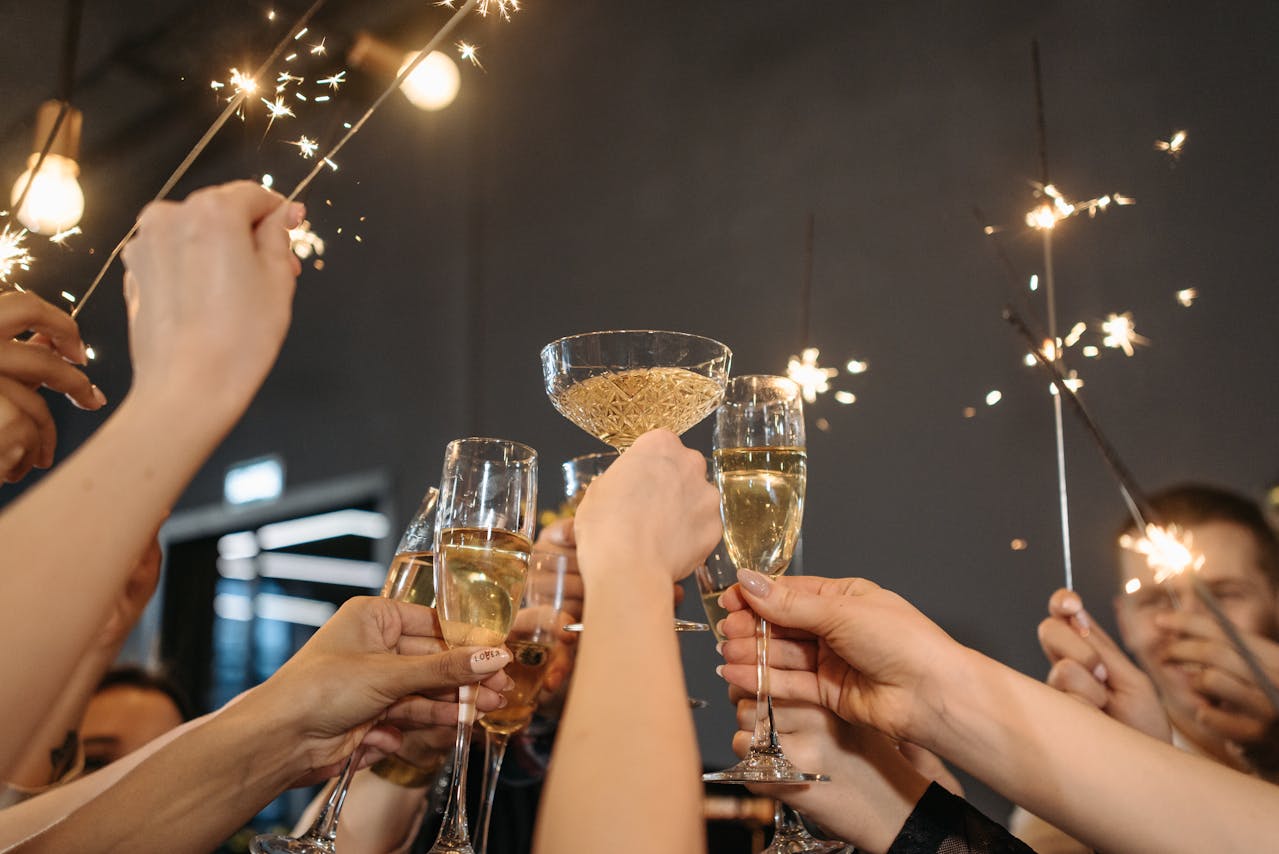 people with lit sparklers toasting with glasses of champagne on a rooftop with a city skyline in the background